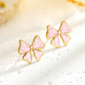 Macro shot of pink marble texture bow earrings with elegant golden stainless steel borders
