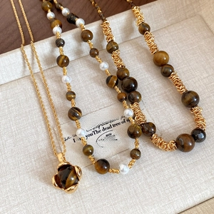 Detailed view of vintage tiger eye stone and pearl necklace with retro gold accents
