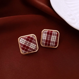 Détail de boucles d'oreilles carrées en tissu écossais rouge avec bordure dorée chic