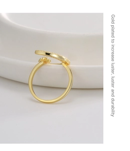 Detail of gold plated moon ring with cubic zirconia stones on white ceramic dish