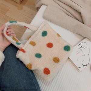 Detailed texture of white plush tote bag with vibrant green and orange polka dots