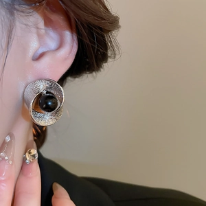 Detail eines silbernen strukturierten Ohrrings mit schwarzer Perle am Modell