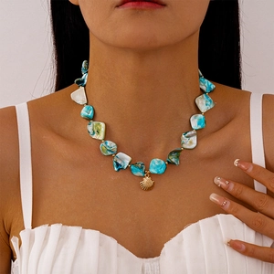 Dettaglio della collana di perline verde acqua con ciondolo a conchiglia dorata su modella