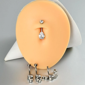 Macro detail of G23 titanium belly button rings with white heart and teardrop zircons