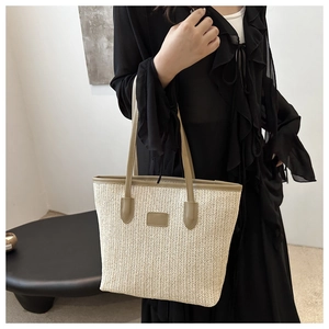 Detailed close-up of straw woven tote bag featuring beige herringbone pattern and leather straps