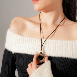 Detail of vintage resin circle pendant necklace on model with black and white sweater