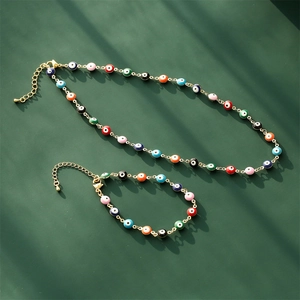 Gold-plated Evil Eye jewelry set including necklace and bracelet on dark green background