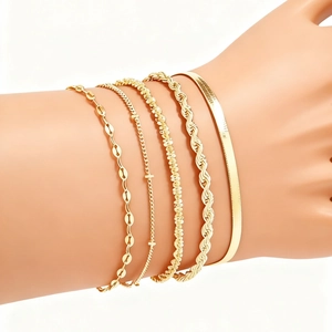 Close-up of stacked bohemian gold plated figaro chains and bangles on a wrist
