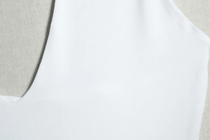 Close-up of high-quality sewing on white halter dress fabric with fine texture detail