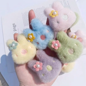 Nahaufnahme weicher Plüsch-Hasenbroschen in Bonbonfarben mit Perlenblumen-Details