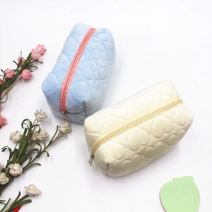 Close-up of heart quilted velvet storage bags in soft blue and beige with metal zippers