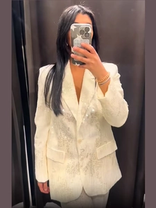 Dettaglio del blazer bianco con paillettes argentate lucide e design del colletto