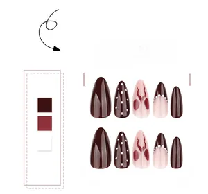 Detail of almond-shaped press-on nails with brown wine red colors and bow patterns