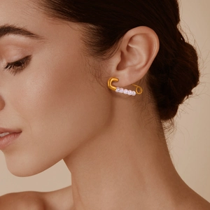 French style gold safety pin earrings with white pearls worn by a model for a stylish look