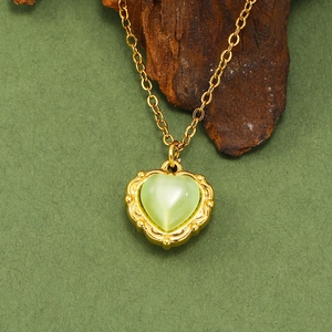 Vue macro du pendentif cœur en opale verte avec cadre doré vintage sur bois brut