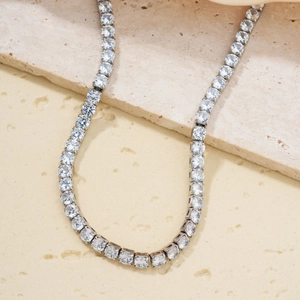 Sparkling silver tennis necklace featuring square-cut cubic zirconia on a stone surface