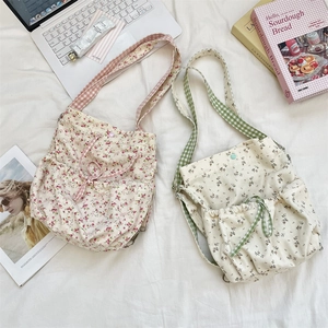 Detail of floral canvas backpacks with checkered straps and drawstring pockets in soft colors