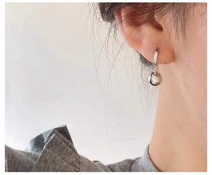 Detailansicht eines minimalistischen Silberohrrings mit poliertem Kugelanhänger am Modell