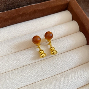 Détail de boucles d'oreilles gourde avec perles d'ambre et métal gravé sur velours