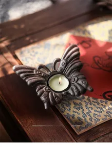 Détail d'un bougeoir papillon vintage en fonte avec bougie allumée sur bois sombre
