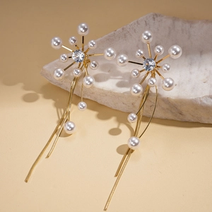 Macro detail of gold flower earrings with radiating pearls and dangling chain tassels