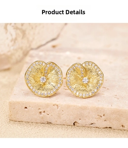 Macro shot of gold silver lotus leaf earrings with brushed texture and zircon details