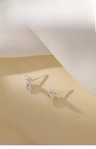 Detailed close-up of colorful butterfly zircon stud earrings on silk fabric