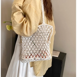 Handmade woven cotton rope shoulder bag with hollow mesh design and tassel detail for beach
