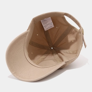 Detail van beige katoenen baseballcap met binnennaden en wasvoorschrift label