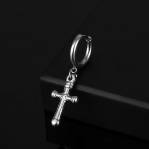 Close-up of polished silver stainless steel cross pendant earring on a black jewelry stand