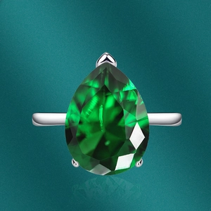 Macro shot of pear-cut emerald gemstone ring with three-prong silver setting details