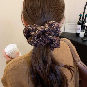 Détail d'un chouchou en tweed marron café avec paillettes sur une queue de cheval