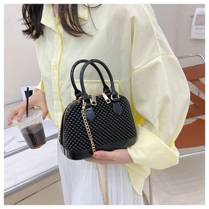 Detail of black shell-shaped jelly bag with beaded texture and golden chain strap
