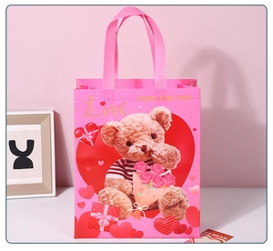Pink non-woven gift bag featuring a teddy bear holding roses and golden Love text