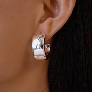 Detailed close-up of polished silver wide C-shape earring showing mirror-like metallic finish