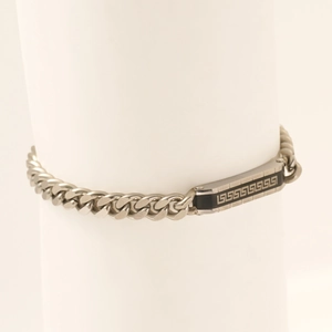 Macro detail of silver Cuban chain bracelet featuring a black Greek fret pattern plate