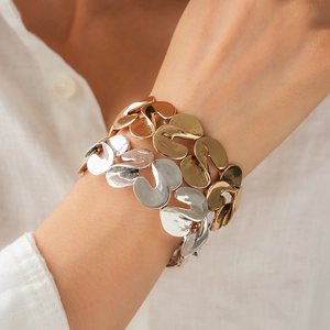Close-up of gold and silver S-shaped metallic link bracelets worn on the wrist