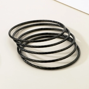 Macro detail of five black twisted steel wire bracelets with vintage industrial texture