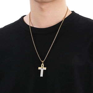 Close-up of a two-tone gold and silver cross pendant worn by a male model on a black shirt