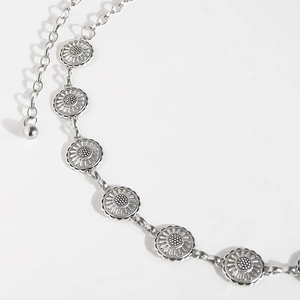 Detail of silver daisy chain belt featuring intricate floral metal links and adjustable tail
