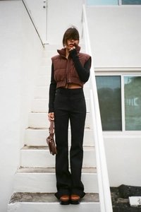 Short stand-up collar puffer vest paired with black high-waist flared pants and chunky boots