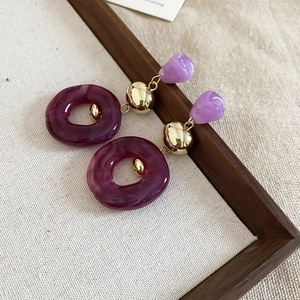 Detailed view of purple acrylic drop earrings with marble texture on a linen display