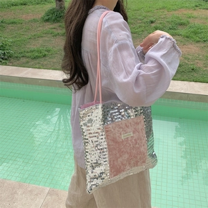 Outdoor shot of a silver sequin tote bag with pink suede pocket worn by a model
