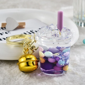 Close-up of a creative purple liquid mini drink cup keychain with a golden bell and ring