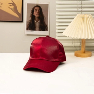 Elegant burgundy satin baseball cap with a smooth glossy finish for women in a studio set