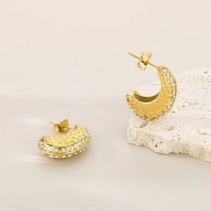 Détail de boucles d'oreilles C dorées 18 carats avec texture martelée et zircons