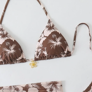 Close-up of triangle bikini top with floral print and golden flower pendant detail
