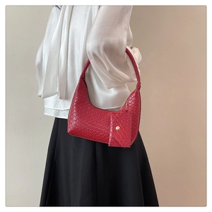 Detail of red woven texture handbag with matching mini charm pouch on shoulder strap