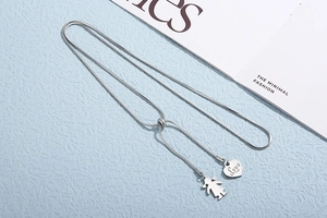 Detailed view of silver heart and girl silhouette charms on adjustable snake chain