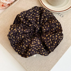 Close-up of a purple leopard print satin scrunchie featuring an elegant pearl charm detail